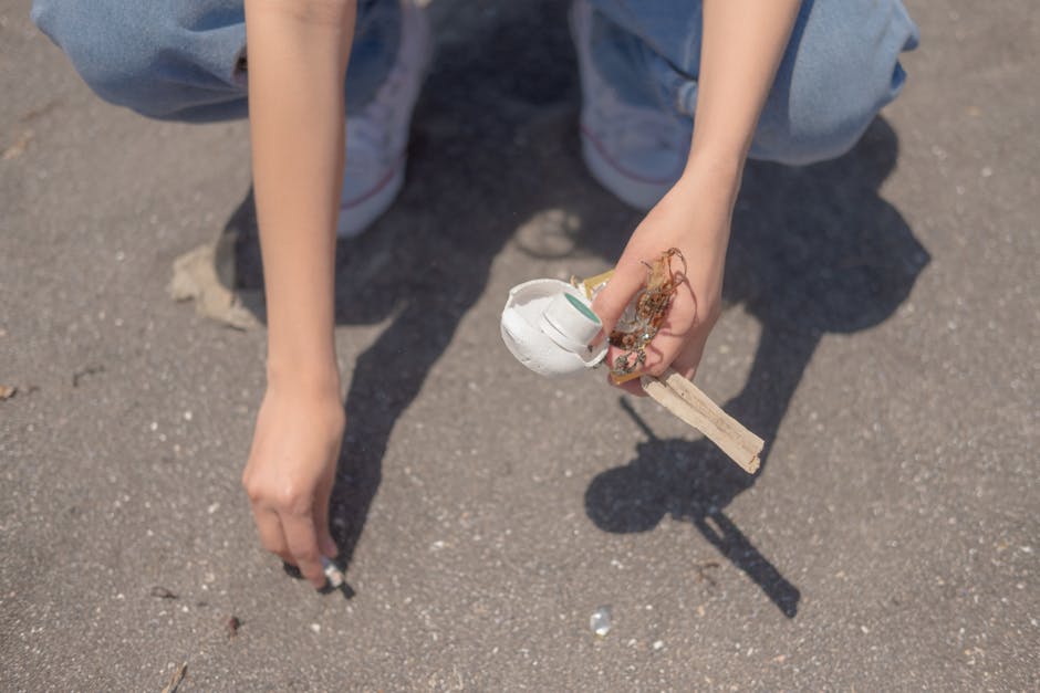 A person wearing white gloves and a wristwatch is holding a large white sack filled with garden debris, including small branches, green leaves, and assorted plant material. The sack appears to be made